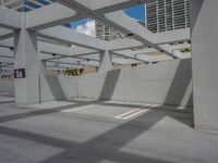 a concrete parking garage and a clear blue sky with white columns and beams above the concrete