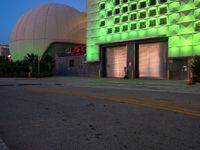 a green light adorns the side of the building near a yellow fire hydrant