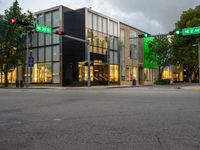 an intersection in the center of an urban area that has large windows with a lite and two red traffic lights