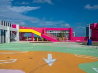 the children's playground area is brightly painted and features colorful slides, a colorful wall, and a yellow playground slide