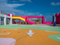 the children's playground area is brightly painted and features colorful slides, a colorful wall, and a yellow playground slide