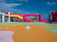 the children's playground area is brightly painted and features colorful slides, a colorful wall, and a yellow playground slide