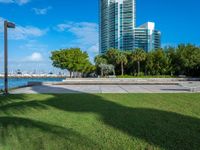 view to the city from a park with benches and green grass along shore in miami