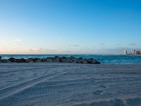 a sandy beach next to the ocean on a sunny day and with a sky background