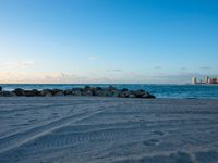 a sandy beach next to the ocean on a sunny day and with a sky background