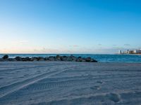 a sandy beach next to the ocean on a sunny day and with a sky background