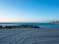 a sandy beach next to the ocean on a sunny day and with a sky background