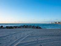 a sandy beach next to the ocean on a sunny day and with a sky background