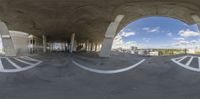 view from inside a concrete building, of multiple white arrows drawn in it, and into an open walkway with sky behind