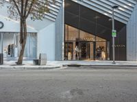 two women walking outside of a clothing store near trees and buildings with two people on bikes passing by