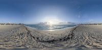 a view of the ocean with sand and sun in background at sunset time, in a fish eye lens