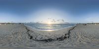 a 360 - view fish eye lens looking at people walking on the beach at sunset