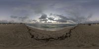 a panoramic photo of the sun breaking in over the ocean and a person sitting on a bench at the beach