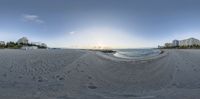 a photo of the sun setting over a beach with footprints in the sand and a body of water