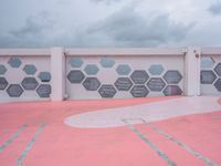 the wall is covered with red cement tiles and hexagon shaped panels that resemble windows