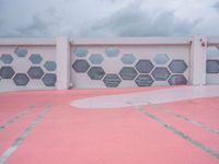 the wall is covered with red cement tiles and hexagon shaped panels that resemble windows