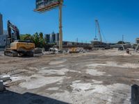 two construction vehicles in a construction site with people walking nearby in the background and under the blue sky