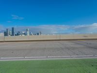 a highway with two lanes and no parking on it with a city skyline in the background