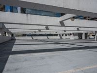 a building with multiple windows has benches in the middle of the space and shadows cast across the concrete