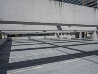 a building with multiple windows has benches in the middle of the space and shadows cast across the concrete