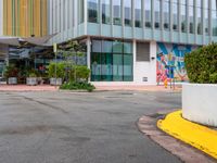 the curb is made from concrete and has plants in pots on it in front of the building