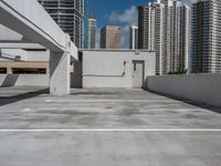 a white parking lot with no cars on top of it and some tall buildings in the background