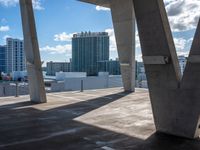 large concrete pillars near several building and sky scrapes in the background with clouds in the sky