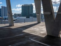 large concrete pillars near several building and sky scrapes in the background with clouds in the sky