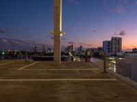 a street lamp sitting on top of a metal pole near water and buildings with tall, glass windows