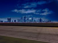 an empty highway with city skyline behind it at night time, lit up by red lights