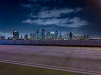 an empty highway with city skyline behind it at night time, lit up by red lights