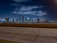 an empty highway with city skyline behind it at night time, lit up by red lights