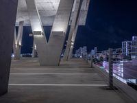 a city skyline at night with several very tall pillars lit up in bright light with a bench at the edge