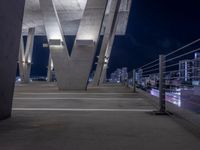 a city skyline at night with several very tall pillars lit up in bright light with a bench at the edge