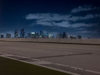 a city skyline with buildings lit up at night from the roadway at dusk with streetlights glowing at night