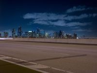 a city skyline with buildings lit up at night from the roadway at dusk with streetlights glowing at night