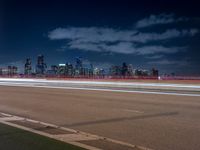 a city skyline with buildings lit up at night from the roadway at dusk with streetlights glowing at night