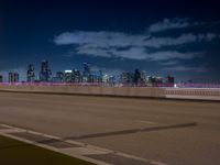 a city skyline with buildings lit up at night from the roadway at dusk with streetlights glowing at night