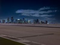 a city skyline with buildings lit up at night from the roadway at dusk with streetlights glowing at night