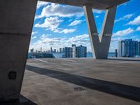 the view of an empty building in a city from underneath a concrete structure with the city below