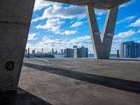 the view of an empty building in a city from underneath a concrete structure with the city below