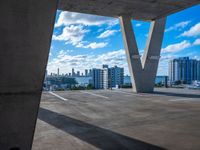 the view of an empty building in a city from underneath a concrete structure with the city below