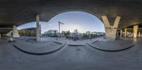 a wide angle view of some buildings from a ramp looking into a big tunnel with a skateboarder at the bottom