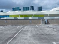 a parking lot with many empty buildings in the background and clouds in the sky above