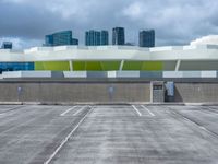 a parking lot with many empty buildings in the background and clouds in the sky above