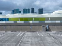 a parking lot with many empty buildings in the background and clouds in the sky above