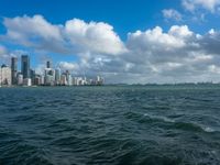 the city skyline is visible from a large body of water in front of it is partly cloudy skies