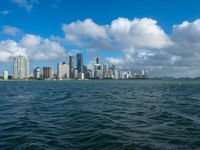 the city skyline is visible from a large body of water in front of it is partly cloudy skies