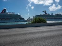 the large cruise ship is docked at the port next to a street corner with blue sky and clouds