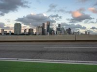 an empty freeway with city in the distance during sunset time against a blue cloudy sky